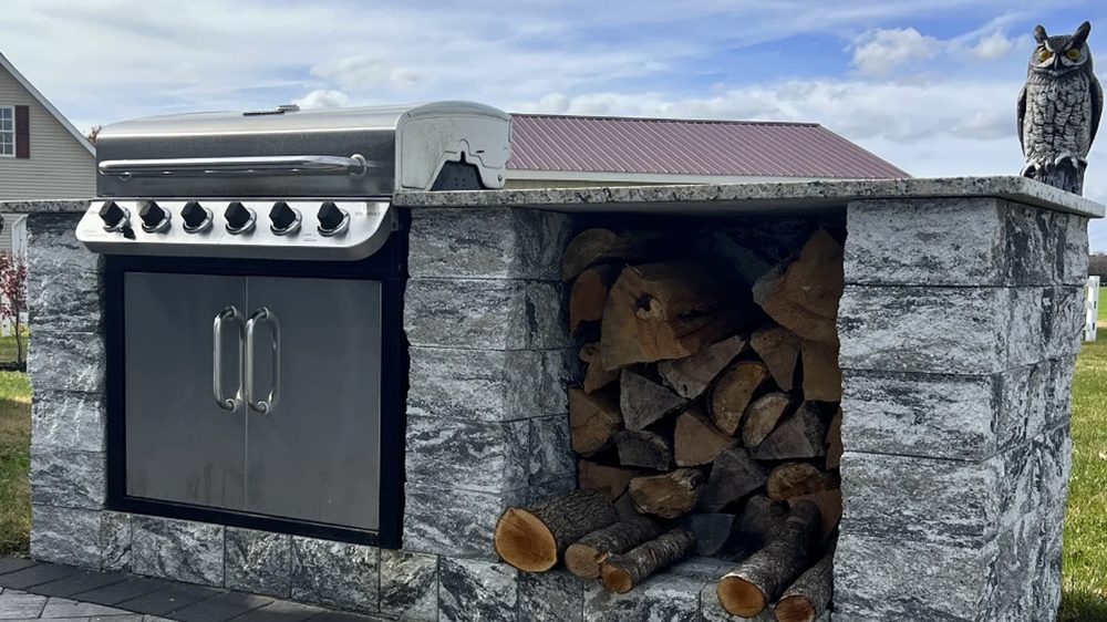 Stone-clad outdoor kitchen with built-in grill and firewood storage